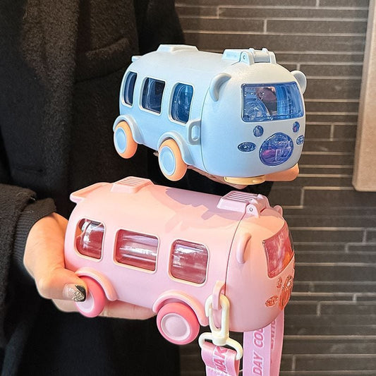 Two water bottle toy buses, one blue and one pink, held by a person against a brick wall.